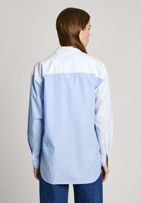 Blauw gestreept shirt met een witte bovenkant, lange mouwen, knoopmanchetten en een rechte zoom. Glad katoenen stof.