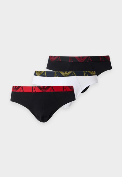 Trois slips pour hommes en noir et blanc, chacun avec une ceinture colorée distincte comprenant un logo et un motif de lettres.