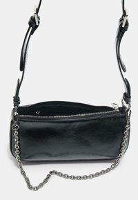 Černá crossbody taška z umělé kůže s řetízkovým popruhem, zipovým uzavřením a hladkým povrchem. Má zaoblený tvar a minimalistický design.