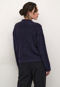 Paarse, fuzzy trui met een hoge halslijn en verlaagde schouders. Kenmerkt zich door lange mouwen en een losse pasvorm, aangevuld met een zachte textuur.