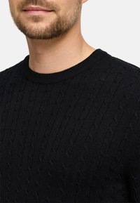 Czarny sweter dzianinowy z teksturowanym wzorem w warkocze, okrągłym dekoltem i prążkowanymi mankietami, wykonany z miękkiego materiału.