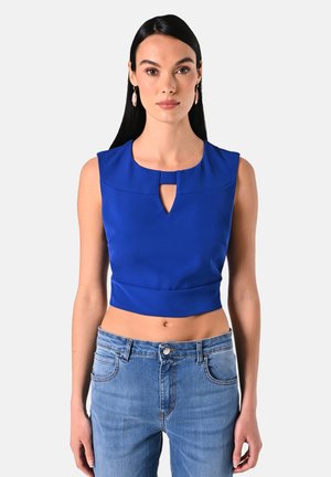 Blauwe, mouwloze crop top met een keyhole halslijn en een aansluitend ontwerp. Gekocht met lichtblauwe jeans, die een gladde stofstructuur laten zien.