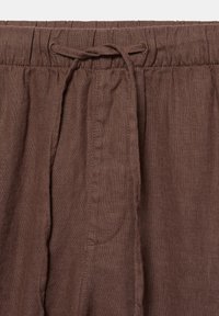 Pantalon en lin marron avec taille élastique et cordon noué devant.