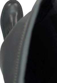 Botte en cuir gris avec un bout arrondi, détails cousus le long des coutures et une texture lisse, vue du dessus sur l'intérieur.