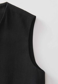 Schwarzes ärmelloses Oberteil mit glatter Textur und klaren Linien. Verfügt über einen bescheidenen Ausschnitt und dezenten Nähten an den Armlöchern.