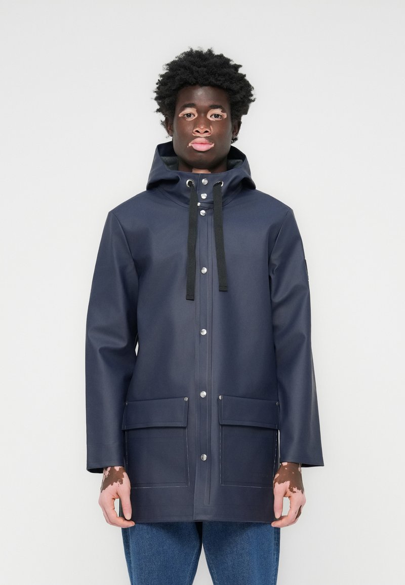 Marineblaue wasserdichte Regenjacke mit Kapuze, Druckknopfverschlüssen, Kordelzügen und zwei Fronttaschen. Glatte Textur mit geradem Schnitt.