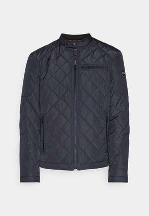 Námořnický prošívaný kabát se stojáčkem, zipem vpředu a bočními kapsami. Obsahuje diagonální prošívání a logo na rukávu.