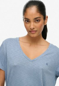 Lyseblå V-hals t-shirt med korte ærmer og en blød tekstur; har et diskret broderet logo på brystet.