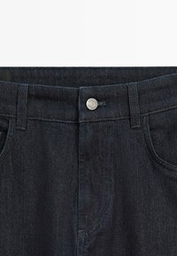 Jeans in denim blu scuro con un design classico, chiusura con bottone frontale, cinque tasche e una texture liscia.