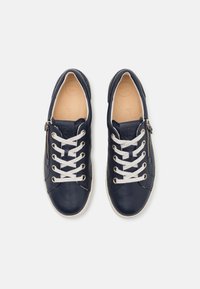 Granatowe skórzane trampki z białymi sznurówkami, z zamkiem błyskawicznym z boku, okrągłym noskiem, teksturowanym wierzchem i beżowym wnętrzem. Lekka konstrukcja.