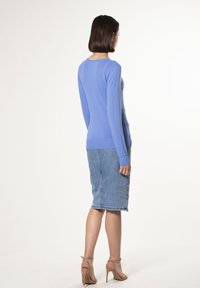 Lichtblauw aansluitend sweater met lange mouwen, ronde halslijn, gecombineerd met een denim kokerrok. Gladde textuur, eenvoudig ontwerp, enkelband hakken.
