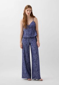 Ensemble débardeur à motifs bleus et pantalon large en tissu texturé. Bretelles spaghetti et coupe décontractée. Les chaussures comprennent des talons simples.