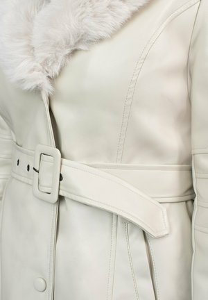 Abrigo de cuero crema con cuello de piel sintética, cinturilla ceñida, costuras visibles y detalle de botón a presión en el lateral. Textura suave y diseño entallado.