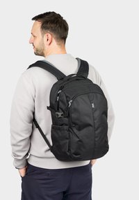 Black backpack with multiple zippered compartments, padded shoulder straps, and a textured fabric finish. Features include side pockets and adjustable clips.