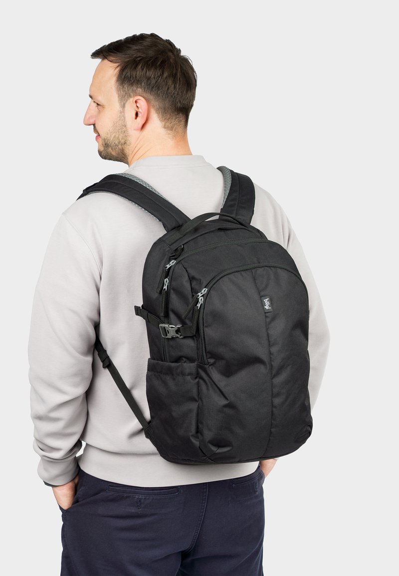 Black backpack with multiple zippered compartments, padded shoulder straps, and a textured fabric finish. Features include side pockets and adjustable clips.