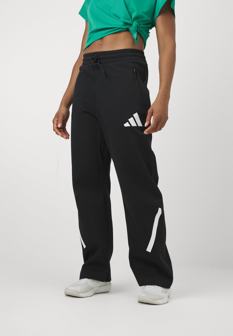 Melnas sporta bikses ar elastīgu jostu, sānu rāvējslēdzēja kabatām un baltu adidas logotipu un akcentiem. Izgatavotas no mīksta, elastīga auduma.