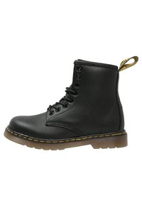 Bottine en cuir noir à lacets, coutures jaunes et languette de talon à logo, avec une semelle en caoutchouc translucide.