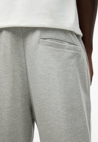 Grijze joggingbroek met een zachte textuur en een elastische tailleband. Voorzien van een klein, vlak achterzakje en zichtbare stiksels.