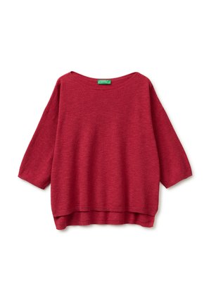 Czerwony sweter z teksturowanym splotem, z rękawami o długości do połowy przedramienia i nieco dłuższym tylnym brzegiem, z okrągłym dekoltem oraz zieloną metką marki.