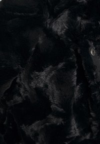 Sort imiteret pelsstof med en blank, glat tekstur og varierende pelskorthøjder, der har subtile bølger og en skinnende overflade.