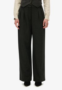 Pantalones de pierna ancha en tela gris oscuro con un patrón de rayas. Presentan pliegues en la cintura y un acabado texturizado sutil.