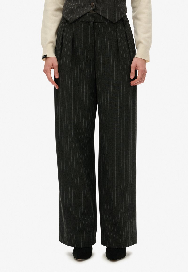Pantalones de pierna ancha en tela gris oscuro con un patrón de rayas. Presentan pliegues en la cintura y un acabado texturizado sutil.