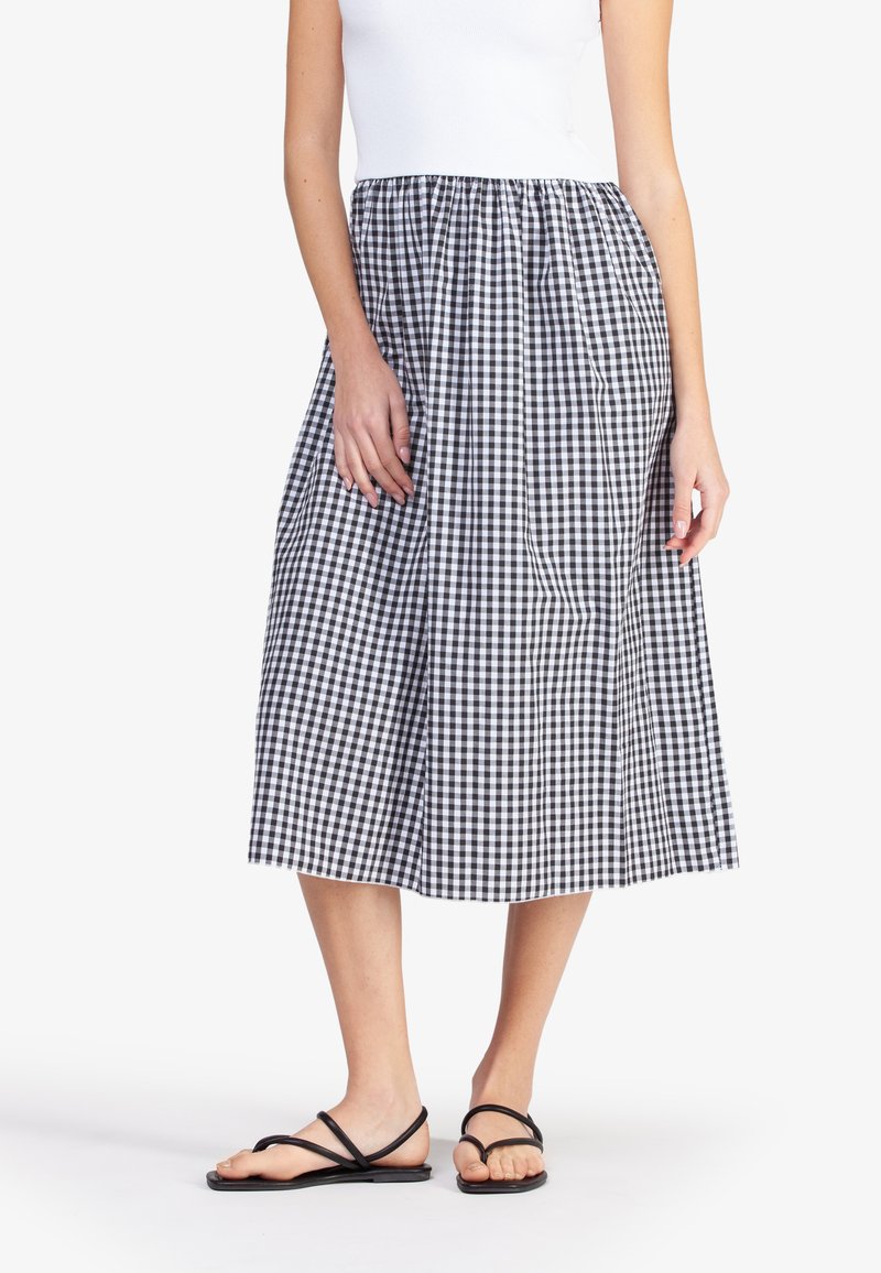 Zwart-witte ruit midi rok met elastische tailleband, twee zijzakken en een losse pasvorm; gecombineerd met zwarte platte sandalen.