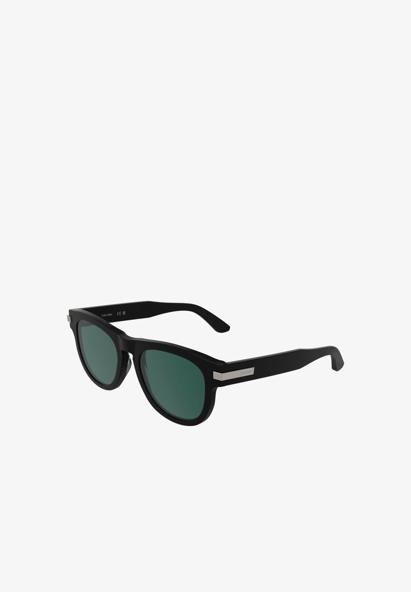 Occhiali da sole rettangolari neri con lenti verde scuro e dettagli argentati sulle aste, inclinati per mostrare la vista frontale e laterale.