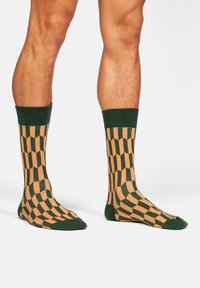 Grüne und beige gemusterte Socken mit geometrischen Designs, einem strukturierten Finish und einem gerippten Bund am oberen Ende.