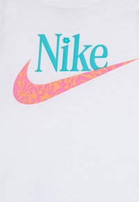 Hvit bomull t-skjorte med en teal "Nike"-logo og en rosa og oransje mønstrete swoosh. Dramatisk design med glatt tekstur.