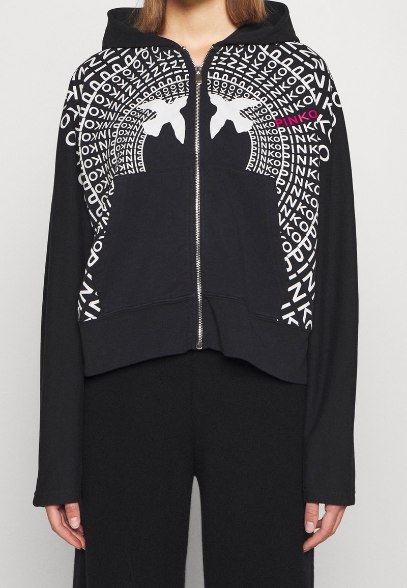 Hoodie zippé noir avec un design graphique en texte blanc et rose accompagné de formes abstraites. Le matériau semble doux et extensible.