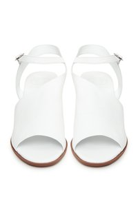 Valkoiset nahkasandaalit, joissa on avoin varvas, ristikkäissuunnittelu ja nilkkaremmi. Varustettu littealla ruskealla pohjalla ja sileällä pinnalla.