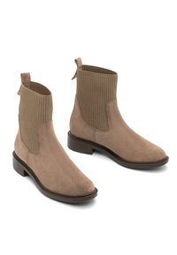 Šviesiai smėlio spalvos zomšiniai aulinukai iki kulkšnies su elastingomis juostelėmis, apvaliu pirštu ir žemu sukrautu kulnu. Yra užtrauktukas, kad būtų lengva apsiauti.