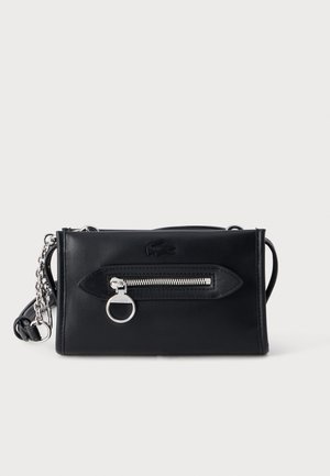 Sac bandoulière rectangulaire en cuir noir avec poche zippée argentée à l'avant et bandoulière chaîne argentée sur fond uni.