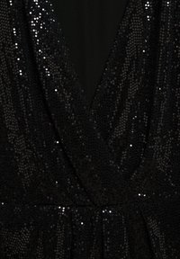 Tissu à sequins noirs avec décolleté en V profond et détail froncé à la taille sur un vêtement.