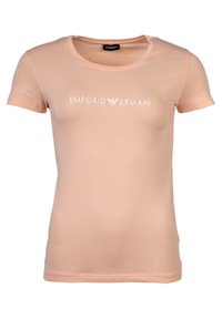 Camiseta de manga corta color melocotón hecha de una tela suave, con escote redondo y un logo blanco de "Emporio Armani" en el pecho.