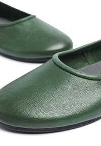Scarpe slip-on in pelle verde con una texture liscia, punta arrotondata e apertura stretta nella parte superiore. Suola in gomma nera.