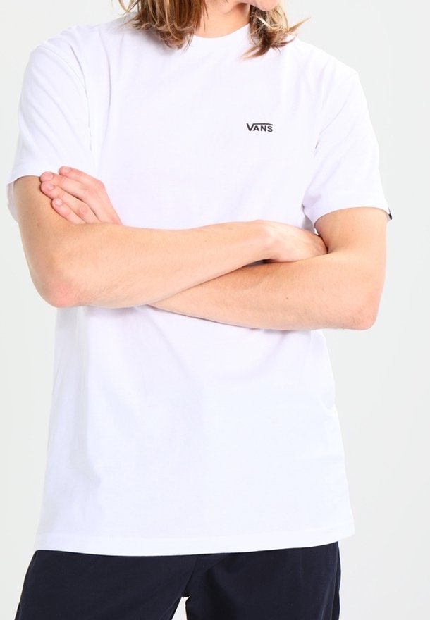 T-shirt blanc à manches courtes en coton avec un col rond et un logo "VANS" noir sur la poitrine gauche. Texture lisse, coupe décontractée.