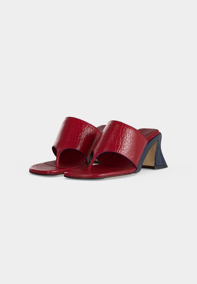 Κόκκινα δερμάτινα πέδιλα με ανοικτά δάχτυλα, φαρδιές λουρίδες και γωνιώδεις μπλοκ τακούνια σε ναυτικό μπλε χρώμα σε λευκό φόντο.