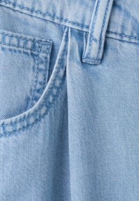Tissu en denim bleu clair avec couture visible de poche et piqûres de passants de ceinture en gros plan.