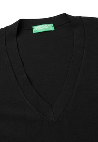 Svart V-halströja med en grön etikett inuti kragen som säger "UNITED COLORS OF BENETTON."