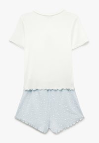 Haut blanc à manches courtes avec des bords en forme de vagues associé à un short bleu clair avec un motif étoilé et un tissu texturé.