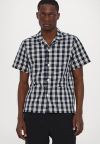 Καρό πουκάμισο κοντομάνικο σε να�υτική μπλε και λευκό, με κουμπιά μπροστά, γιακά και δύο μπροστινές τσέπες.