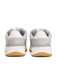 Grey and white sneakers with a textured suede and smooth leather upper, featuring a rubber sole and "TOMMY JEANS" logo on the heel.