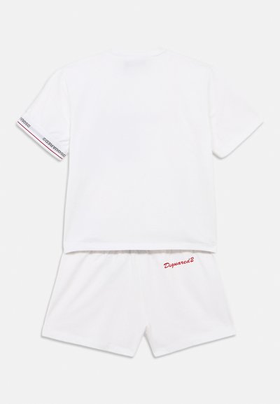 Ensemble t-shirt à manches courtes et short en coton blanc. Le t-shirt présente des accents à rayures rouges sur les manches ; le short est brodé du logo "Dsquared2" en rouge.