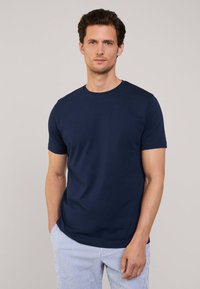 T-shirt bleu marine en coton à col rond, avec des manches courtes, texture lisse, associé à un pantalon rayé. Design simple et classique.