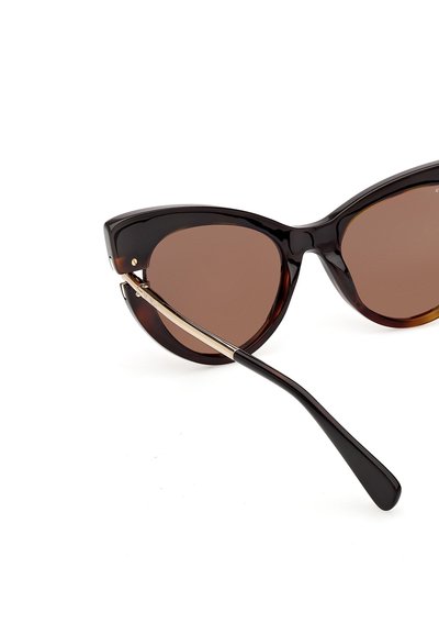 Lunettes de soleil œil de chat brun foncé avec des verres teintés marron et de fines touches dorées sur les branches, sur fond blanc.