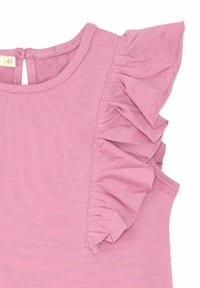 Růžové tričko s volánkovými krátkými rukávy, kulatým výstřihem a klíčovou dírkou na zádech. Vyrobeno z měkké, lehké tkaniny.