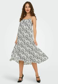 Hihaton mekko valkoisesta kankaasta mustilla pystysuorilla raidoilla. Väljä A-linjainen muotoilu, keskipitkä helma ja hienovarainen liike.