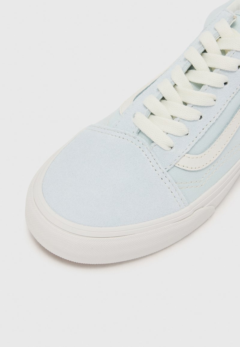 Zapatillas de ante azul claro con suela de goma blanca, cordones planos y rayas laterales blancas en contraste con detalles texturizados.
